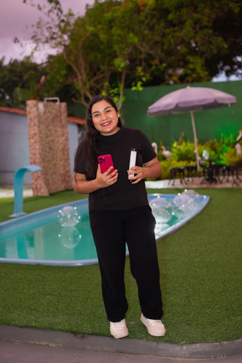 Eduarda Nunes, storymaker, segurando celular e luz de vídeo